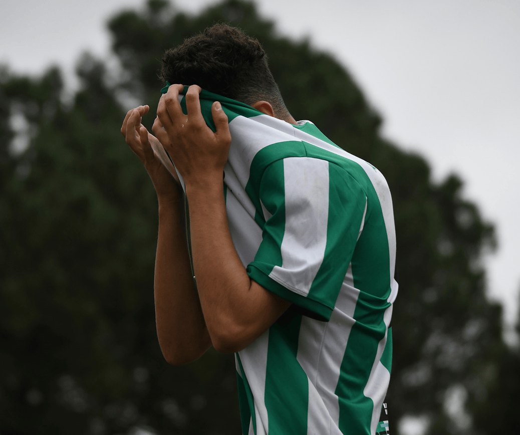 Tired young footballer holding his head